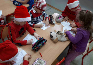 Dzieci przy stolikach wykonują labirynt - próbują wskazać Mikołajowi drogę do domu